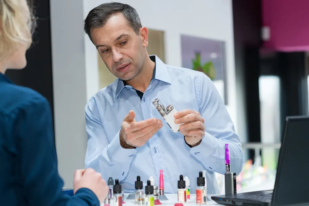 A man explaining the e-cigarette feature to a customer
