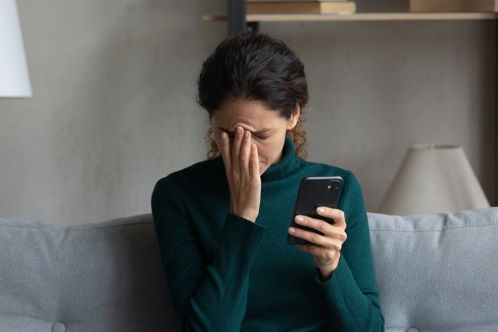 A woman is frustrated, looking at her phone