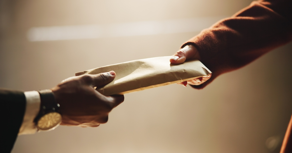 An envelope is handed to a man, suspected of money laundering