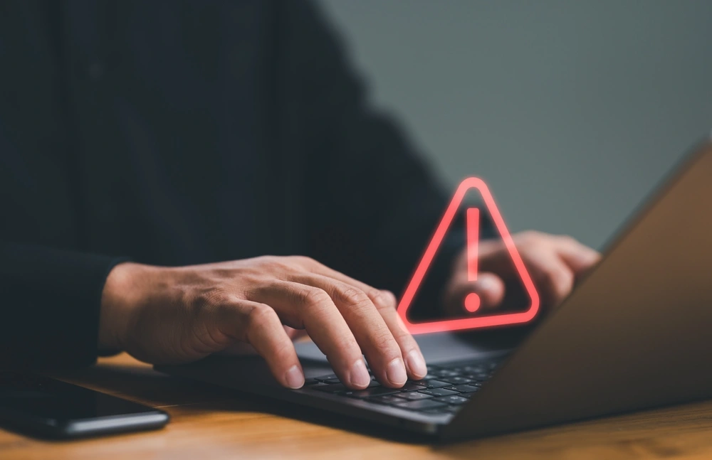 Businessman or it staff , programmer, developer using computer laptop with triangle caution warning sign