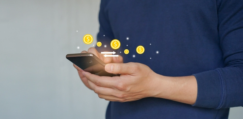 A young man holding a smartphone and use currency transfer application to change or make a transaction.