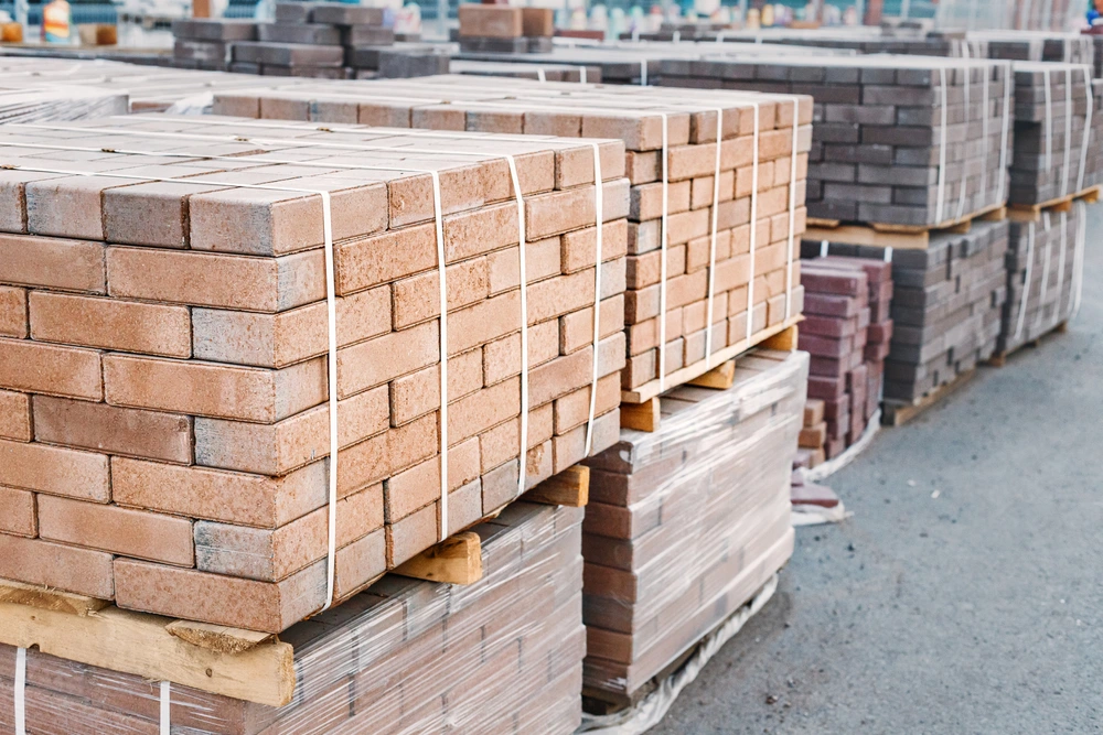 pallets and packages of freshly produced red bricks in a construction warehouse on the street.
