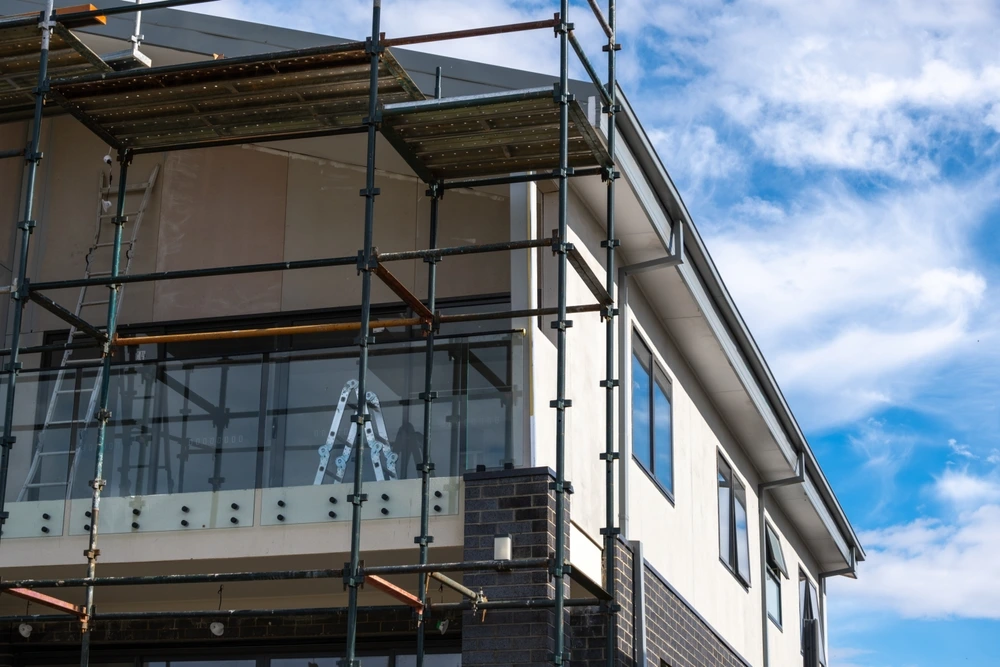 An almost finished new suburban two story house construction project with metal scaffold.