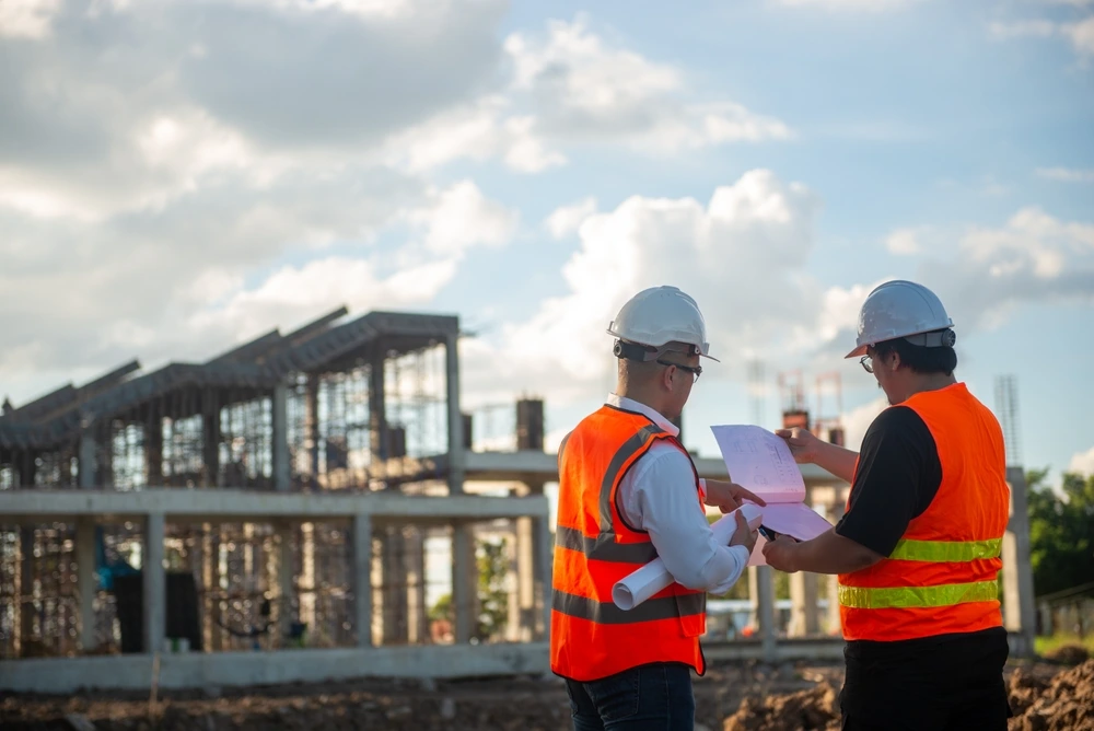 Two architects are standing and discussing building plans and checking the completion of construction